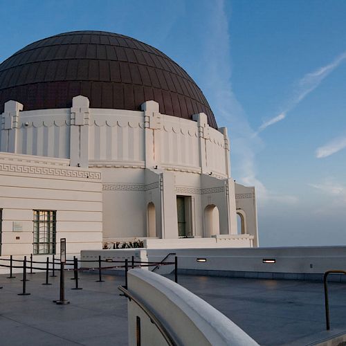 An image of an observatory with a large dome, featuring an open terrace and clear blue sky in the background.