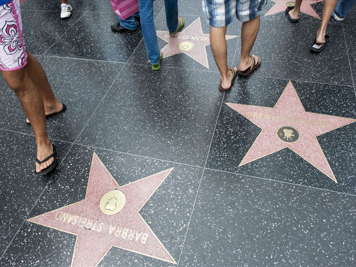 People walking on the Hollywood Walk of Fame, where stars with celebrity names are embedded in the sidewalk.